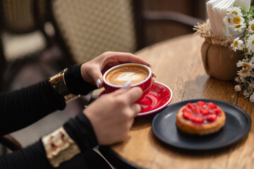 Coffee Dessert Cafe: Woman enjoying cappuccino, strawberry tart on wooden table outside at daytime.