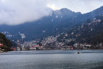 Foggy lake surrounded by dark, cloud-covered mountains in Nainital. 