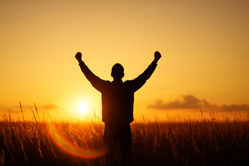 Silhouette of Person Raising Fists at Sunrise in Field
