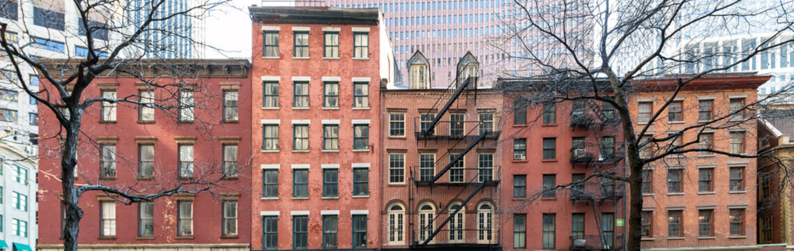 Old historic apartment buildings on Pearl Street in New York City with the modern buildings of the financial district in the background