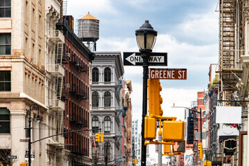 One way sign in front of historic buildings at the busy intersection of Broadway and Greene Street in the SoHo neighborhood of New York City