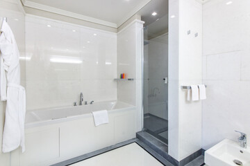 A snow-white bathroom with a bathtub, a glass door to the shower and a sink.