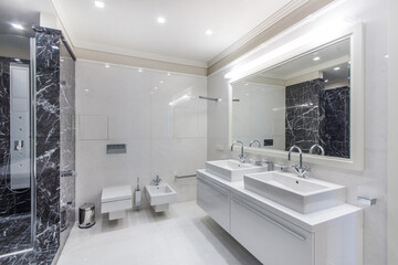The bathroom is decorated with black and white tiles with a shower and a large mirror over the sink.