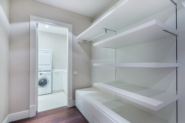 A special room with white wardrobes for clothes. Entrance to a room with a washing machine installed.