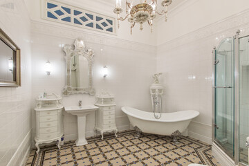 Luxury bathroom in a classic style. Stylish bathtub on curved legs-paws. White furniture.