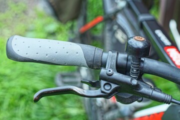 one comfortable gray new modern rubber soft stylish handle on black iron handlebar with brake lever and round bell sport mountain bike daytime outdoor