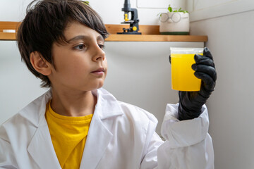 Young boy checking science project with vibrant yellow liquid