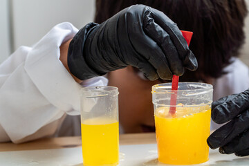 Focused schoolboy in science class stirring liquid in school lab