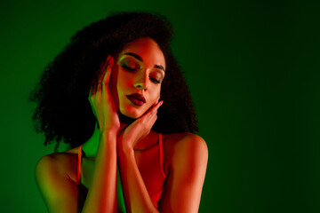 Passionate female portrait with vibrant green lighting highlighting her chic style and graceful...