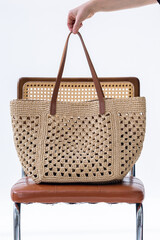 Female hand holding fashionable woven bag. Fashion and luxury accessories. Vertical photo. High...