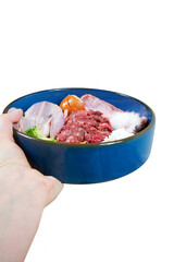 Natural fresh raw dog food. In the woman's hand is a dog's bowl of food Raw meat, quail, egg, rabbit ear with fur, cottage cheese, vegetables. Isolated on white background