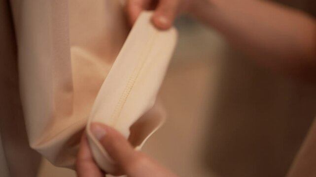 Close-up hands of female seamstress inspecting seam on sleeve of garment, ensuring high-quality stitching and attention to detail in fashion industry. Tailor checking stitching along sleeve seam.