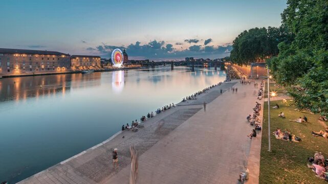 Aerial view of Port de la Daurade park along the Garonne River day to night transition timelapse in Toulouse, France. La Grave Hospital with Saint-Pierre Bridge during sunset with colorful clouds