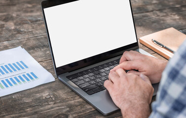 Male entrepreneur analyzing monthly conversion and click-through analytics on laptop at wooden table workspace. Remote work and data analysis concept