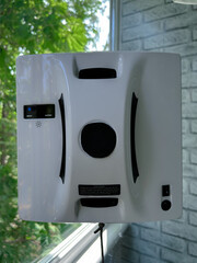 Automated window cleaning robot attached to a glass window in a residential setting. The smart device is in action. Concept of smart home technology, automation, and modern cleaning 