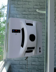 Automated window cleaning robot attached to a glass window in a residential setting. The smart device is in action. Concept of smart home technology, automation, and modern cleaning 