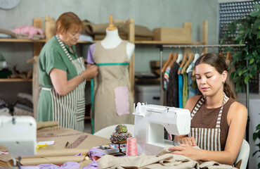 Seamstress works on a sewing machine and stitches fabric against the background of an experienced...