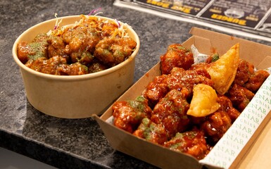 Korean deep dried spicy red chicken sauce in a paper takeaway box.