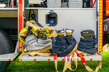 Firefighting gear ready for action – boots, pants, and jackets arranged on the side platform of a...