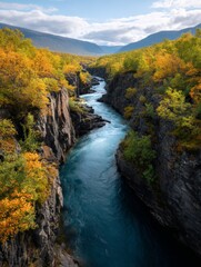 A picturesque autumn landscape featuring a deep mountain valley and a flowing river surrounded by lush greenery and tree foliage in vibrant fall colors.