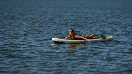Caucasian woman posing on a SUP board. Summer sport.