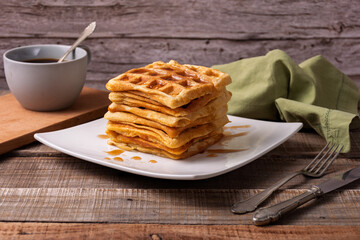 Stack of waffles with caramel coffee cup and cutlery.