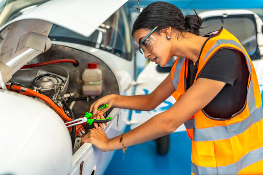 Female aircraft mechanic repairing engine in hangar