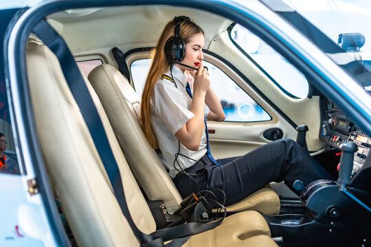 Female pilot preparing for flight, communicating on headset in cockpit