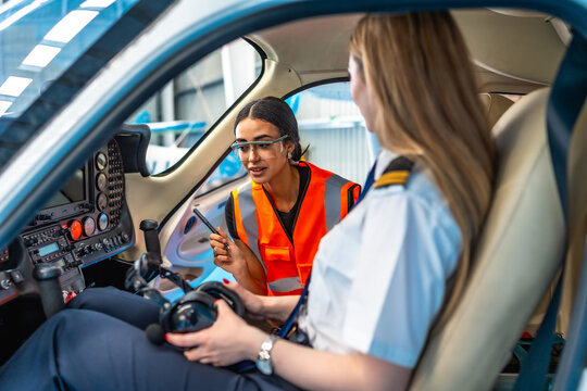 Aircraft maintenance engineer explaining to pilot inside cockpit