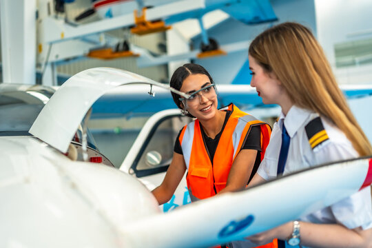 Aircraft maintenance team working together in hangar, pilot and technician discussing maintenance procedures - Powered by Adobe