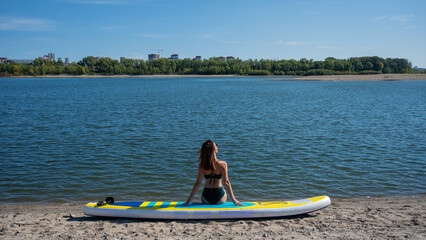 Caucasian woman posing on a SUP board. Summer sport.