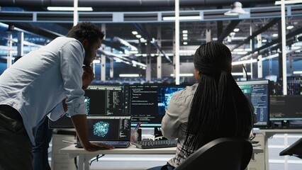 Obraz premium Data center manager supervising worker deploying AI solutions optimizing equipment. Server farm supervisor overseeing programmer using artificial intelligence to minimize systems downtime, camera A