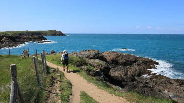 Paysage de c&ocirc;te sauvage &agrave; Saint-Malo en Bretagne, avec un randonneur marchant seul sur le sentier du littoral, au bord de la mer, sur le chemin de grande randonn&eacute;e GR34 (France)