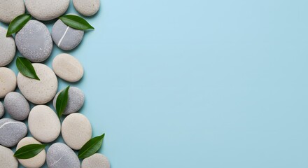 Spa Stones and Green Leaves Border on Blue Background - Wellness, Relaxation, and Beauty Concept