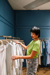 Customer choosing clothes in fashion store boutique retail sales associate browsing merchandise on clothing rack