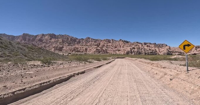 Dirt road in the desert named Quebrada de las Flechas with mountains of sedimentary rocks in Salta Province, Argentina