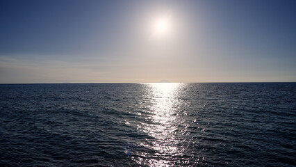 Sunlight reflecting on a calm ocean with an island in the background