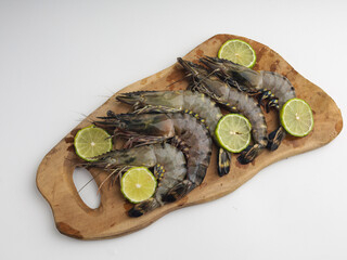 Fresh shrimps or prawns on wooden cutting board with sliced lime