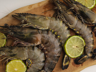 Fresh shrimps or prawns on wooden cutting board with sliced lime