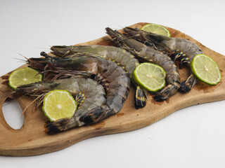 Fresh shrimps or prawns on wooden cutting board with sliced lime