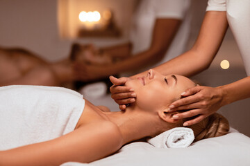 Woman Receiving Face Massage During Relaxing Couples Therapy Enjoying Treatment Lying On Bed In...