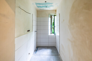 enovated rbathoom with plaster wall and wooden panels at the floor before covered by woodchip wallpaper after wall plastering