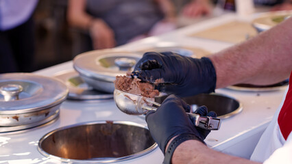 Ice cream vendor preparing a delicious tartufo with chocolate and hazelnut flavors in Pizzo, Italy