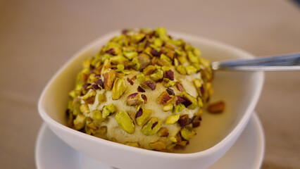 Creamy tartufo dessert covered with pistachios, served in a white bowl with a spoon, a culinary specialty from Pizzo, Italy