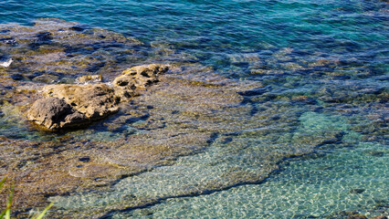 Transparent turquoise water gently flowing over submerged rocks in Pizzo, Calabria, Italy, creating a beautiful natural seascape