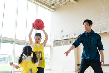 バスケットボールをする子供たちと指導する男性