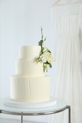 Delicious wedding cake with floral decor on table indoors