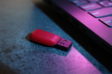 USB flash drive and laptop on dark grey table, closeup