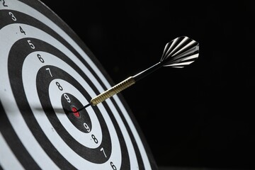 Targeting. Dart board with arrow on black background, closeup