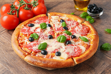 Tasty pizza and ingredients on wooden table, closeup